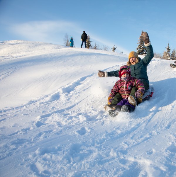 Mother and child going down hill on toboggan