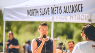 Lady giving speech under North Slave Metis' booth
