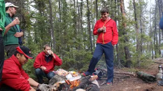 A group of men roasting wieners on the fire 