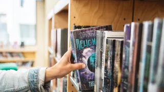 a person selecting a book from the shelf