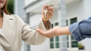 A lady handing over keys to a man