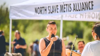 Lady giving speech under North Slave Metis' booth