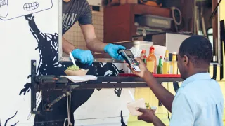 A man paying for his food from a food truck vendor