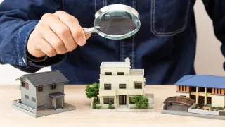 A man using a magnifying glass to closely examine various properties
