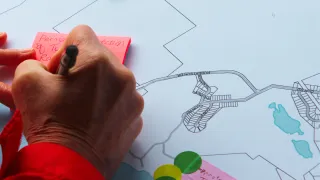 Someone writing on a sticky note on a map